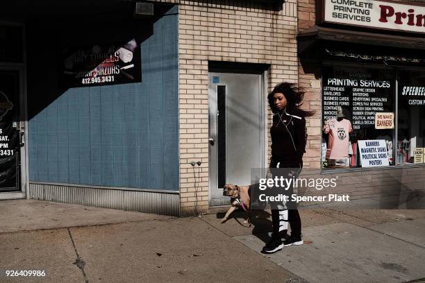Young woman walks her dog down the street in the town of Clairton, home to a United States Steel Corporation plant on March 2, 2018 in Clairton,...