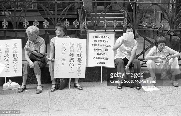 New York - Older Chinese laborers in the Ladies Garment Workers Union sit on the sidewalk with protest signs in Chinatown. They are protesting the...