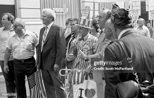 New York - An elderly man dressed as Uncle Sam stands with other laborers and waves an American Flag at a labor union protest in downtown Manhattan....