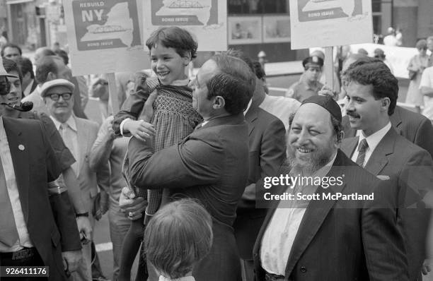 New York - Governor Mario Cuomo holds a young girl in his arms, as he glad hands people on the streets of New York City. Governor Cuomo is pushing...
