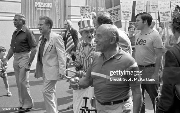 New York - An elderly man dressed as Uncle Sam stands with other laborers and waves an American Flag at a labor union protest in downtown Manhattan....