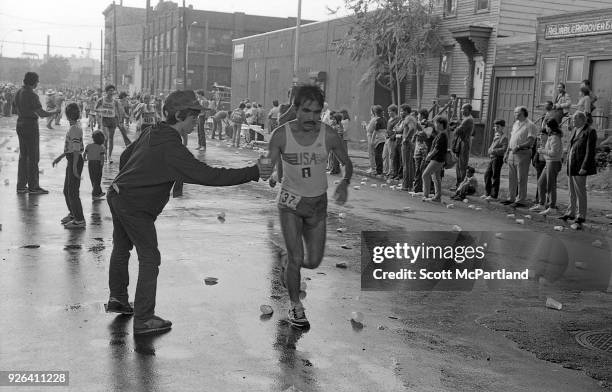 New York - A young boy hands a cup of water to a runner at the 10 mile mark on Bedford Avenue in Williamsburg Brooklyn during the NYC Marathon.