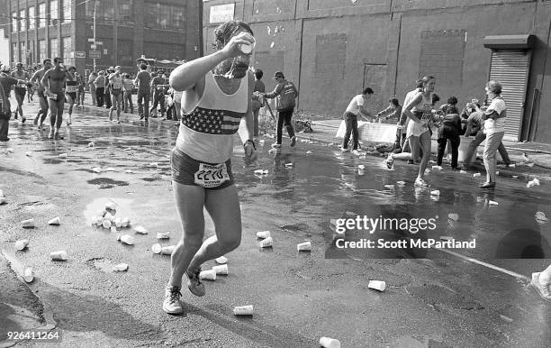 New York - A runner soaked in sweat pours water over his face to cool off during the NYC Marathon.