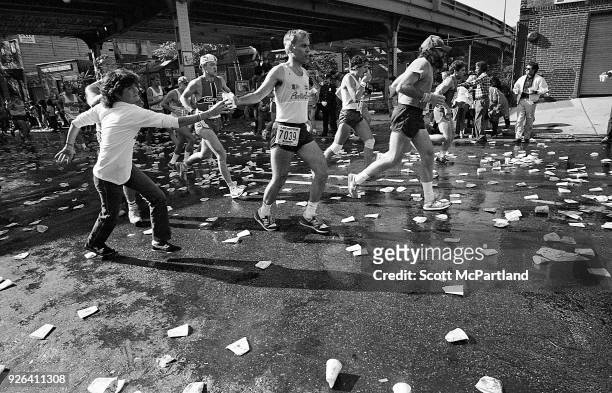 New York - A NYC Marathon volunteer rushes to hand a passing runner a cup of water at the 10 mile mark in Williamsburg Brooklyn.