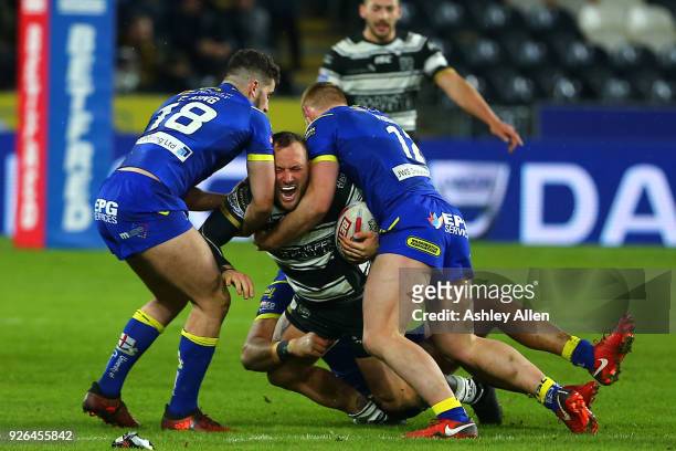Josh Griffin of Hull FC is tackled by Toby King and Jack Hughes of Warrington Wolves during the BetFred Super League match between Hull FC and...