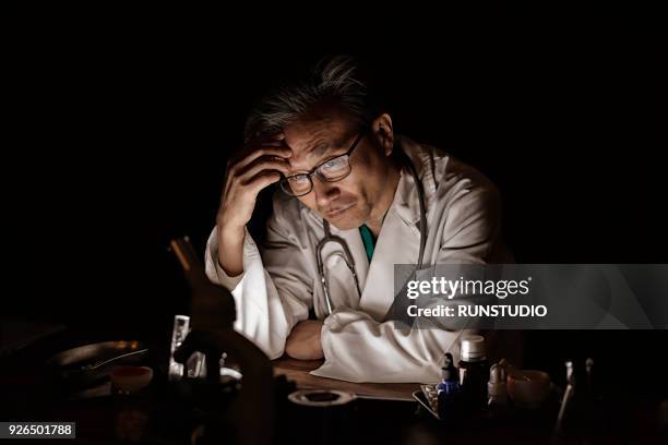 tired and stressed middle aged doctor - matt japan stock-fotos und bilder