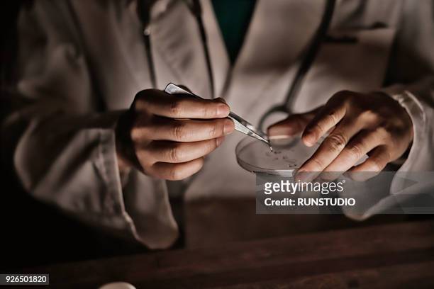 close up of doctor holding tweezers and petri dish - pince chirurgicale photos et images de collection