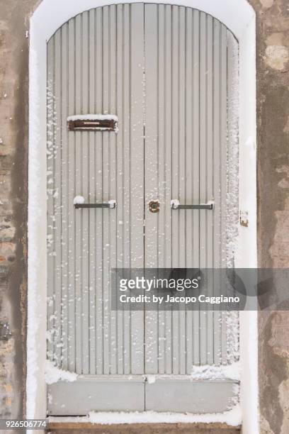 snow on a white painted wooden door - jacopo caggiano foto e immagini stock