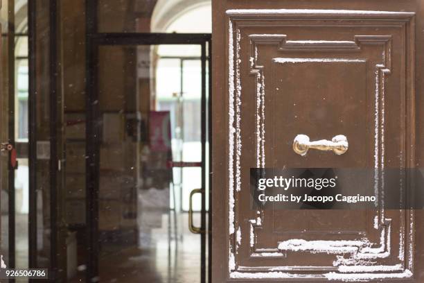 snow on opened wooden door - jacopo caggiano stock-fotos und bilder