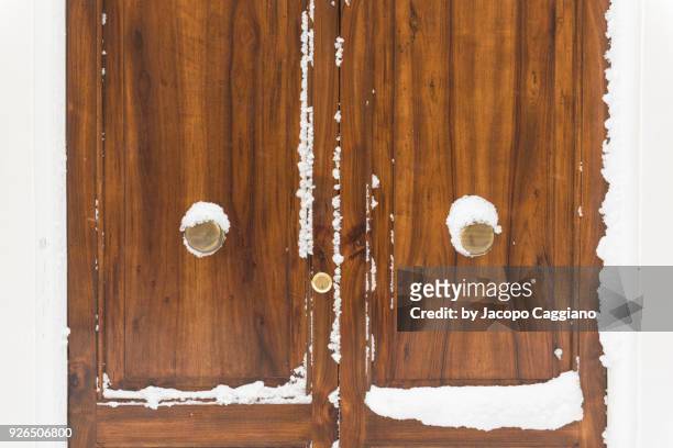 snow on a closed wooden door - jacopo caggiano stock pictures, royalty-free photos & images