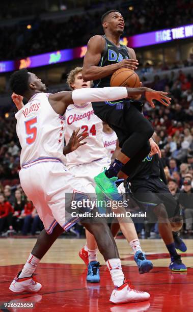 Dennis Smith Jr. #1 of the Dallas Mavericks drives between Bobby Portis and Lauri Markkanen of the Chicago Bulls at the United Center on March 2,...