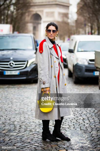 Deborah Reyener Sebag, wearing Burberry grey trench, yellow bag and black boots, is seen in the streets of Paris after the Nina Ricci show during...