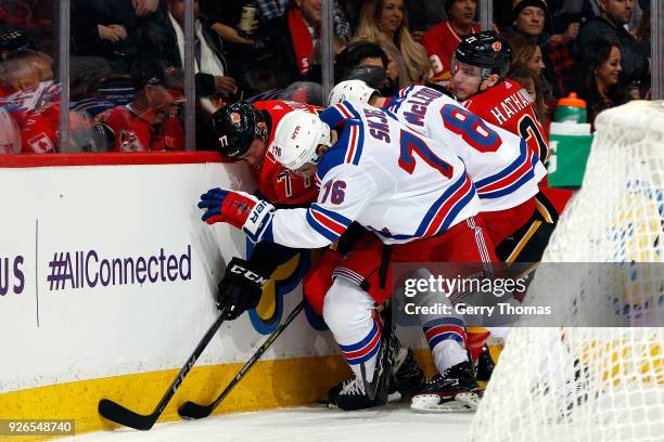 Mark Jankowski and Garnet Hathaway of the Calgary Flames are pinned to the boards by Brady Skjei and Cody McLeod of the New York Rangers during an...