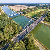 Aerial photograph of infrastructural facilities for cars, trains and ships, overflight of a canal with a railway bridge and a road bridge