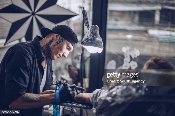 woman getting arm tattoo - tattoo spectacular stock pictures, royalty-free photos & images