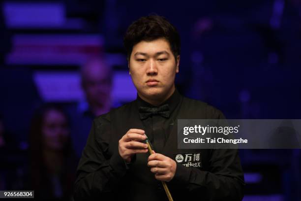 Yan Bingtao of China chalks the cue during his quarter-final match against Barry S. Hawkins of England on day five of 2018 ManBetX Welsh Open at...