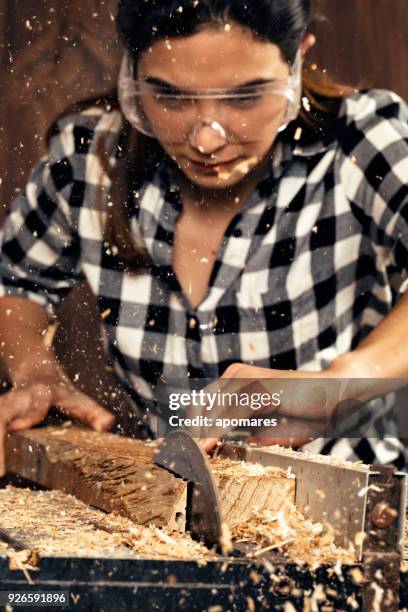 young hispanic carpenter working with table saw with protective eyewear in home workshop - table saw stock pictures, royalty-free photos & images