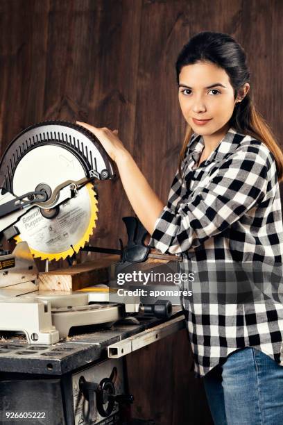 young hispanic carpenter working with single bevel compound miter saw in home workshop - table saw stock pictures, royalty-free photos & images