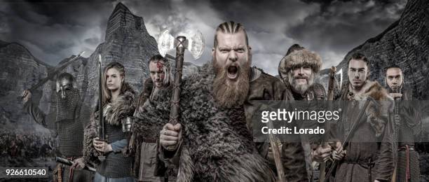 weapon wielding viking warriors in formation in front of viking hoard and mountain range - barbarian stock pictures, royalty-free photos & images