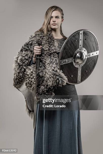 rubia trenzada arma empuñando vikingo guerrero mujer sola en la sesión de estudio - armoured fotografías e imágenes de stock