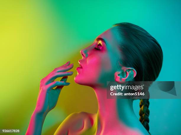 mujer de modelo de alta moda en colores brillantes luces posando en el estudio - alta moda fotografías e imágenes de stock