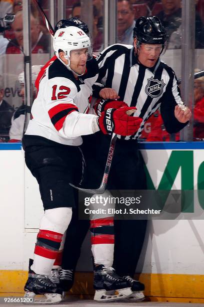 Linesmen Scott Driscoll gets sandwiched by Ben Lovejoy of the New Jersey Devils in the first period against the Florida Panthers at the BB&T Center...