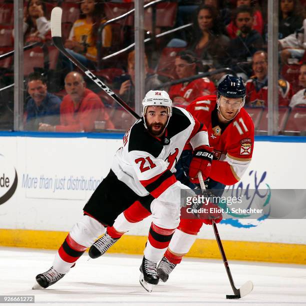 Kyle Palmieri of the New Jersey Devils skates with the puck against Jonathan Huberdeau of the Florida Panthers at the BB&T Center on March 1, 2018 in...