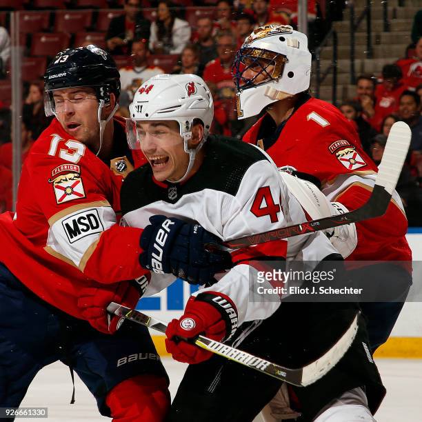 Goaltender Roberto Luongo of the Florida Panthers defends the net with the help of teammate Mark Pysyk against Miles Wood of the New Jersey Devils at...
