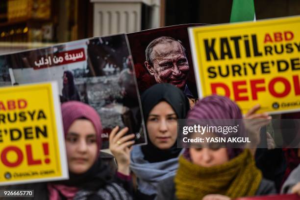 Protesters chant slogans as they hold placards - one featuring an image of Russia's President Vladmir Putin - and wave former Syrian 'independence...