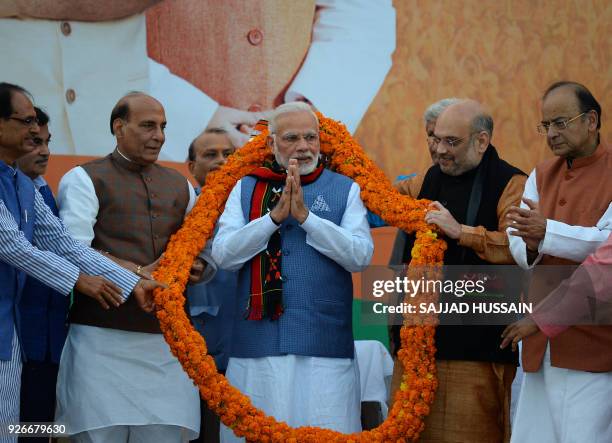 Indian Prime Minister Narendra Modi gestures as he is garlanded by Bharatiya Janata Party leaders during the state election results of three...