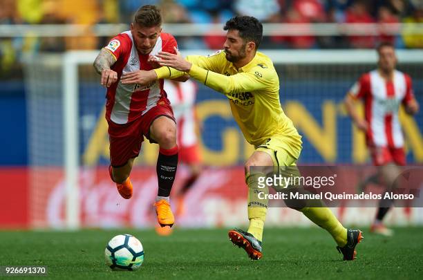 Cristian Portugues of Girona is tackled by Alvaro Gonzalez of Villarreal during the La Liga match between Villarreal and Girona at Estadio de La...