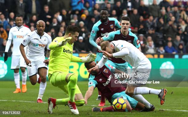Winston Reid of West Ham United sustains an injury in a scrabble for the ball during the Premier League match between Swansea City and West Ham...