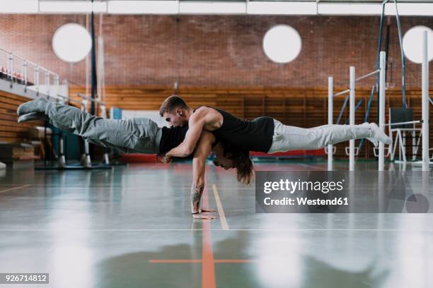 two men doing acrobatics in gym - stabilität stock-fotos und bilder