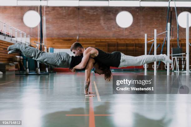 two men doing acrobatics in gym - acrobate photos et images de collection