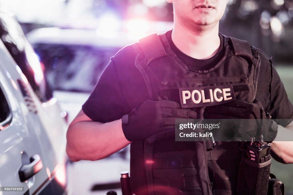 Hispanic police officer wearing bulletproof vest