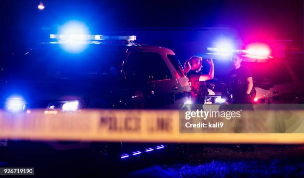 policías de chalecos antibalas detrás cinta cordon - police lights fotografías e imágenes de stock