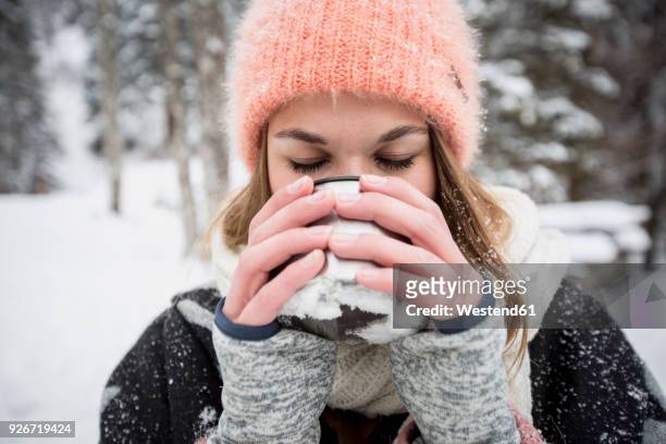 young woman enjoying hot drink outdoors in winter - tea hot drink - fotografias e filmes do acervo