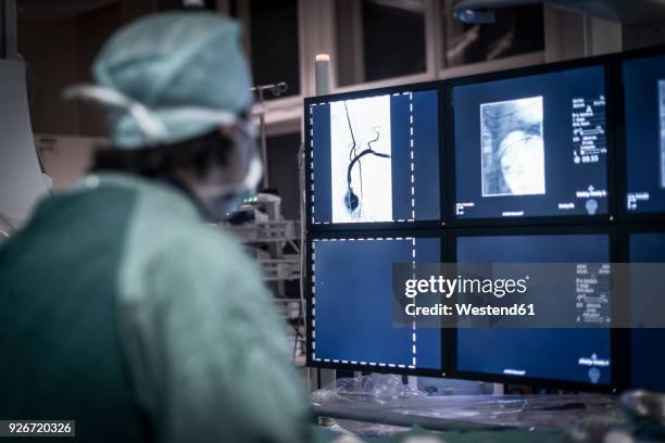 neuroradiologist in scrubs looking at monitor - radiologist stock pictures, royalty-free photos & images