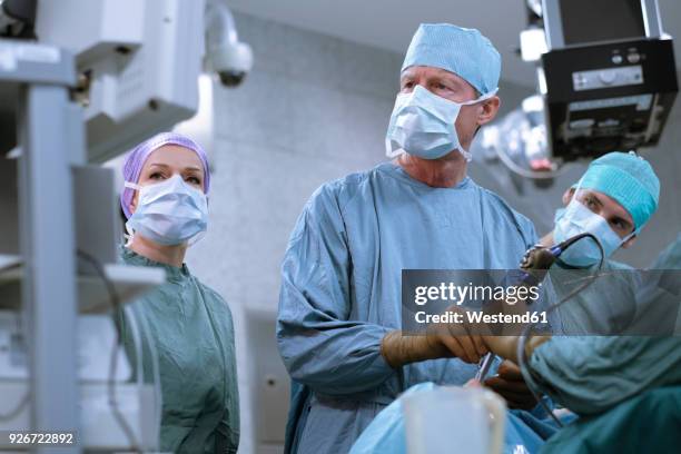 team of neurosurgeons in scrubs during an operation - laparoscopic surgery ストックフォトと画像