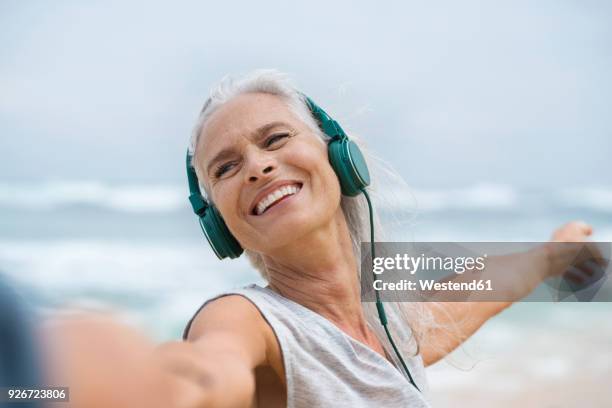 portrait of beautiful smiling senior woman dancing on beach - mann frau leidenschaft stock-fotos und bilder