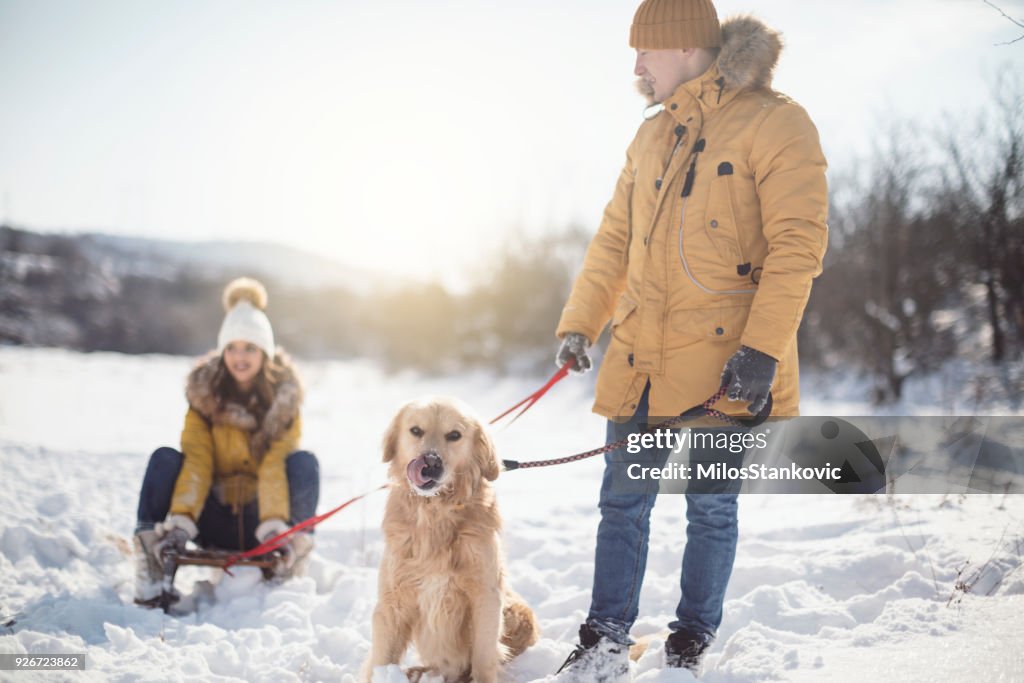 Love couple with dog having fun on snow