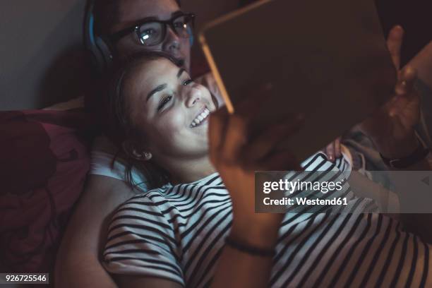 couple lying in bed at home sharing tablet - downloading bildbanksfoton och bilder