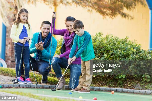 famiglia che gioca a minigolf, ragazzo che mette - minigolf foto e immagini stock