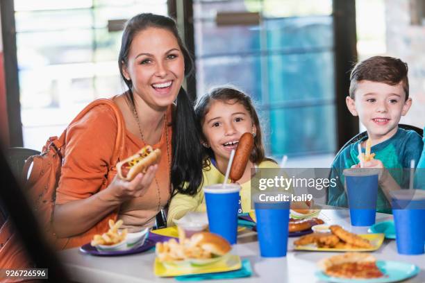 mutter und zwei kinder essen fast food - hot dog schnellimbiss stock-fotos und bilder