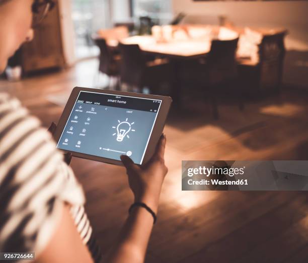 woman using tablet with smart home control functions at home - bombilla de bajo consumo fotografías e imágenes de stock