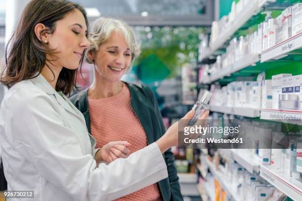 pharmacist advising customer with cosmetics in pharmacy - pharmacy stock-fotos und bilder