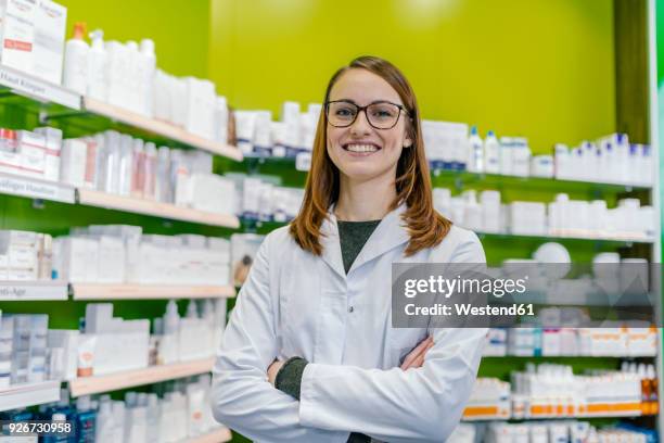 portrait of smiling pharmacist at shelf with medicine in pharmacy - apothekerberuf stock-fotos und bilder