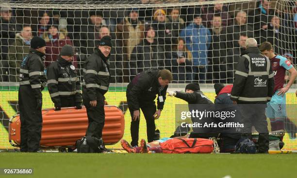 Winston Reid of West Ham United receives intensive treatment before being stretchered off during the Premier League match between Swansea City and...