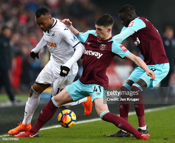 Jordan Ayew of Swansea City holds off Declan Rice and Cheikhou Kouyate of West Ham United during the Premier League match between Swansea City and...