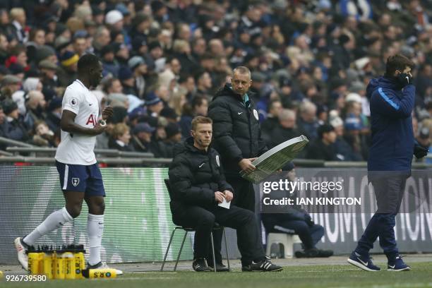 Injured referee Michael Jones sits on the side lines as Tottenham Hotspur's Argentinian head coach Mauricio Pochettino looks on during the English...